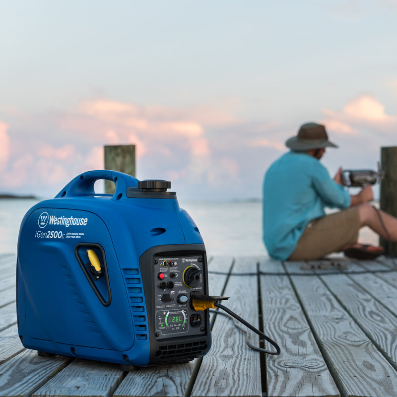 Westinghouse | iGen2500c portable inverter generator shown sitting on a dock while someone uses a power tool that is plugged into the generator