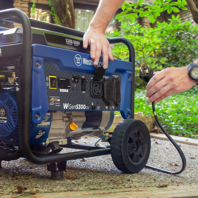 Westinghouse | WGen5300cv portable generator sitting on the ground with a man getting ready to plug a cord into one of the outlets
