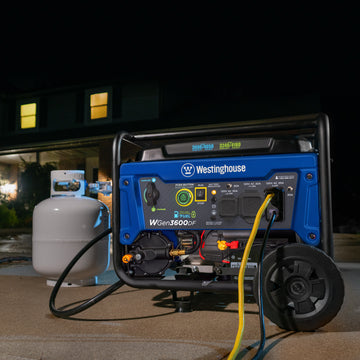 Westinghouse | WGen3600DF portable generator connected to a propane tank sitting on driveway in the dark. There is a house with lights on in the background.