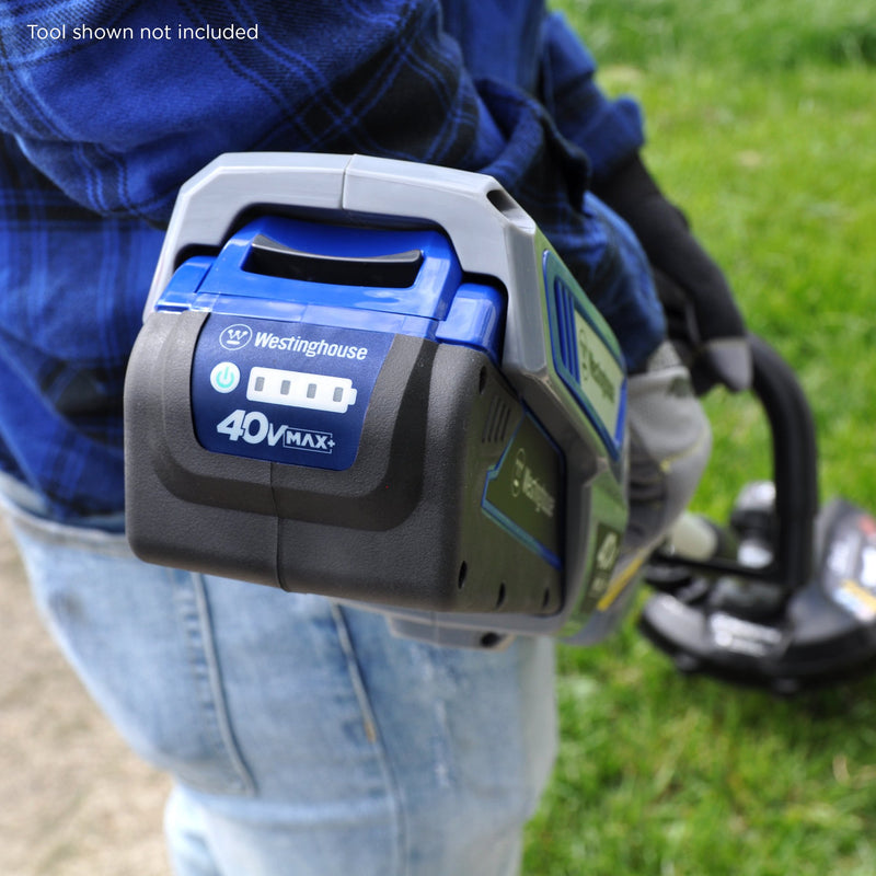 A person uses a 40V string trimmer and edger on the grass. Closeup of the back of the string trimmer showing where the battery plugs in
