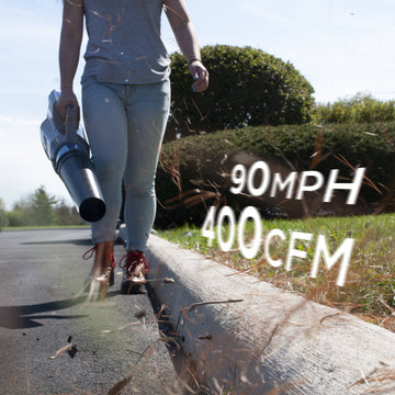 A woman walks towards the camera while using a leaf blower to blow debris off of the street. The text reads "90 mph and 400 cfm".