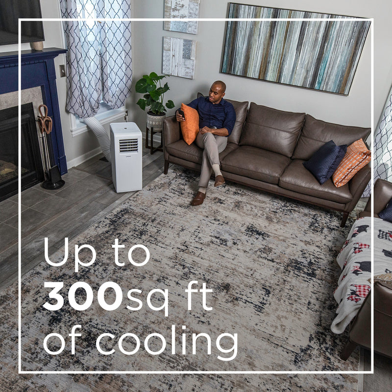 Westinghouse | WPac10000 Portable Air Conditioner shown being used in a living room with a man on the couch on his phone. words at the bottom of the image saying: up to 300 sq ft of cooling