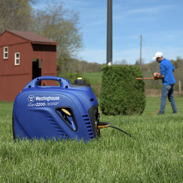 Westinghouse | iGen2200c inverter generator sitting in grass while man works in the background