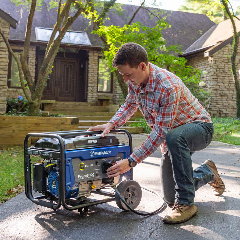 Westinghouse | WGen3600 portable generator sitting on concrete. A man is plugging a cord into the L5-30R outlet.